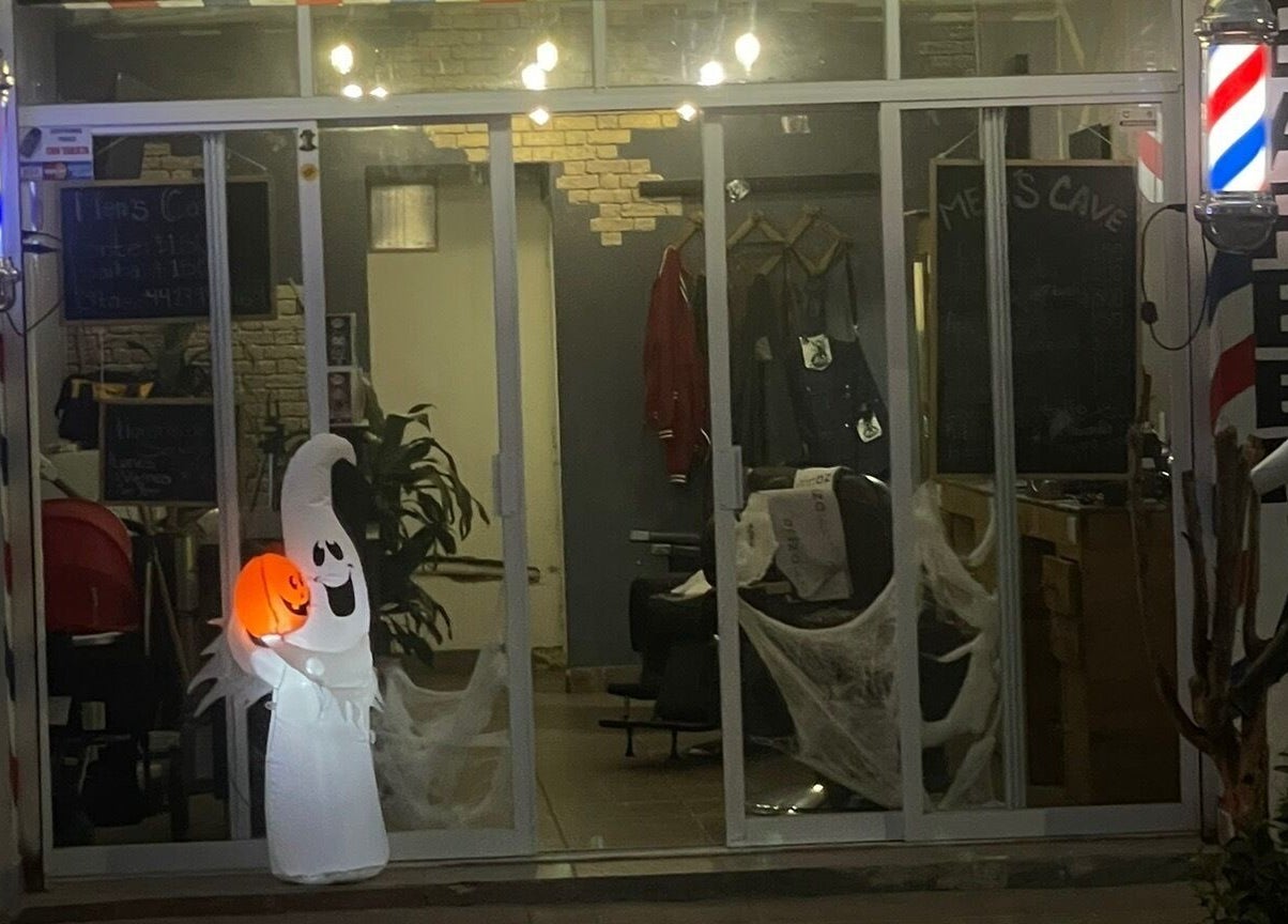 Entrada decorada de Barbería Men's Cave en El Pueblito, Querétaro, MX con un fantasma iluminado.