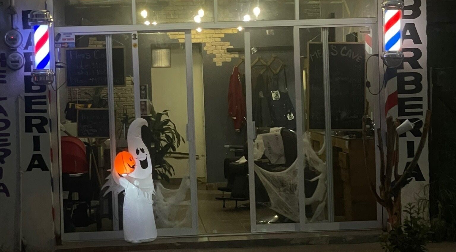 Entrada decorada de Barbería Men's Cave en El Pueblito, Querétaro, MX con un fantasma iluminado.