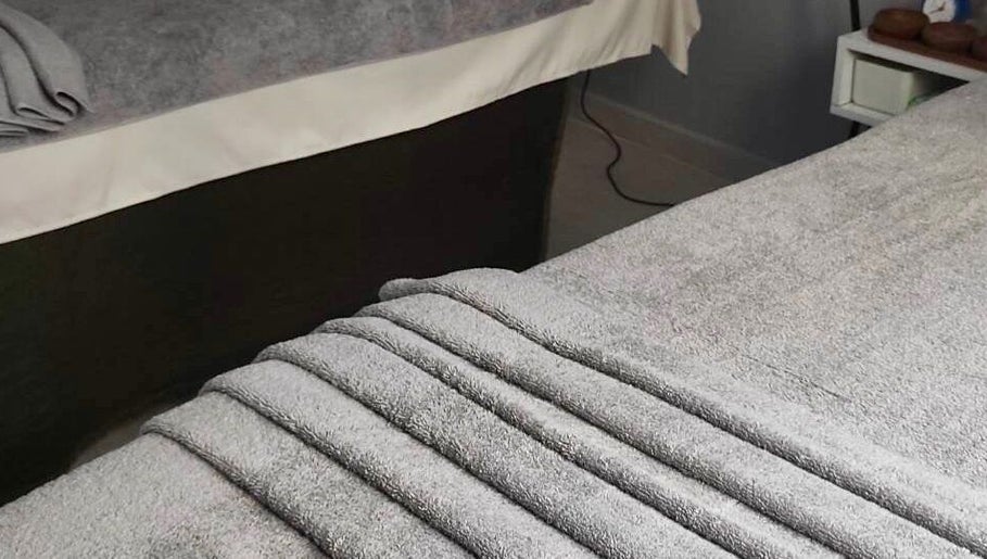 Cozy massage beds with plush gray towels at Real Thai Massage in Athina, GR, providing ultimate relaxation.