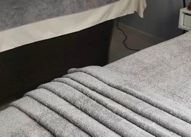 Cozy massage beds with plush gray towels at Real Thai Massage in Athina, GR, providing ultimate relaxation.