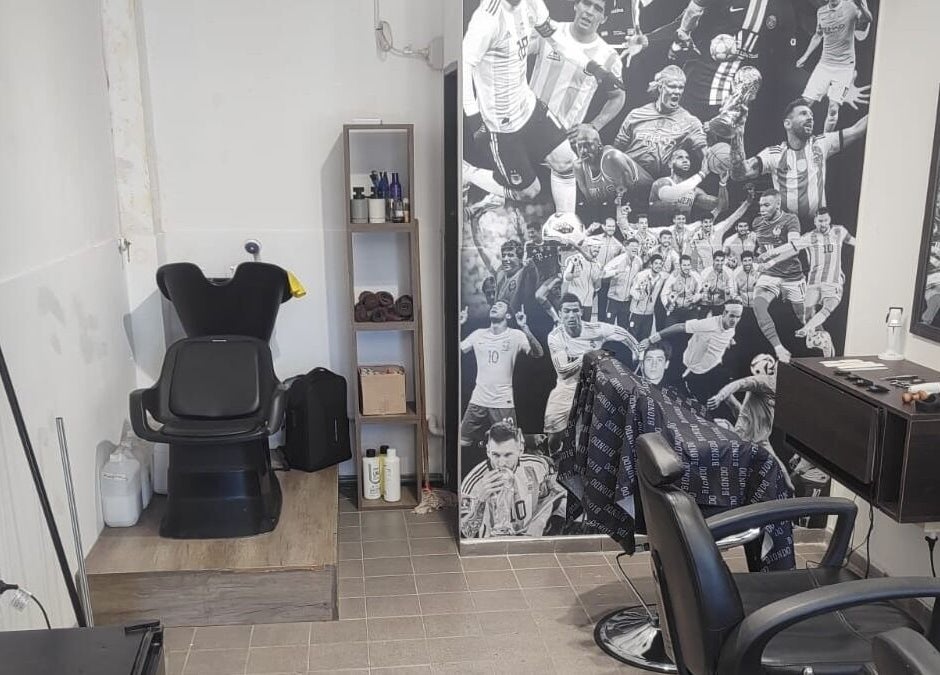 Interior del salón Biondo en San Juan, San Juan, AR, con silla de barbero y decoración de deportistas.