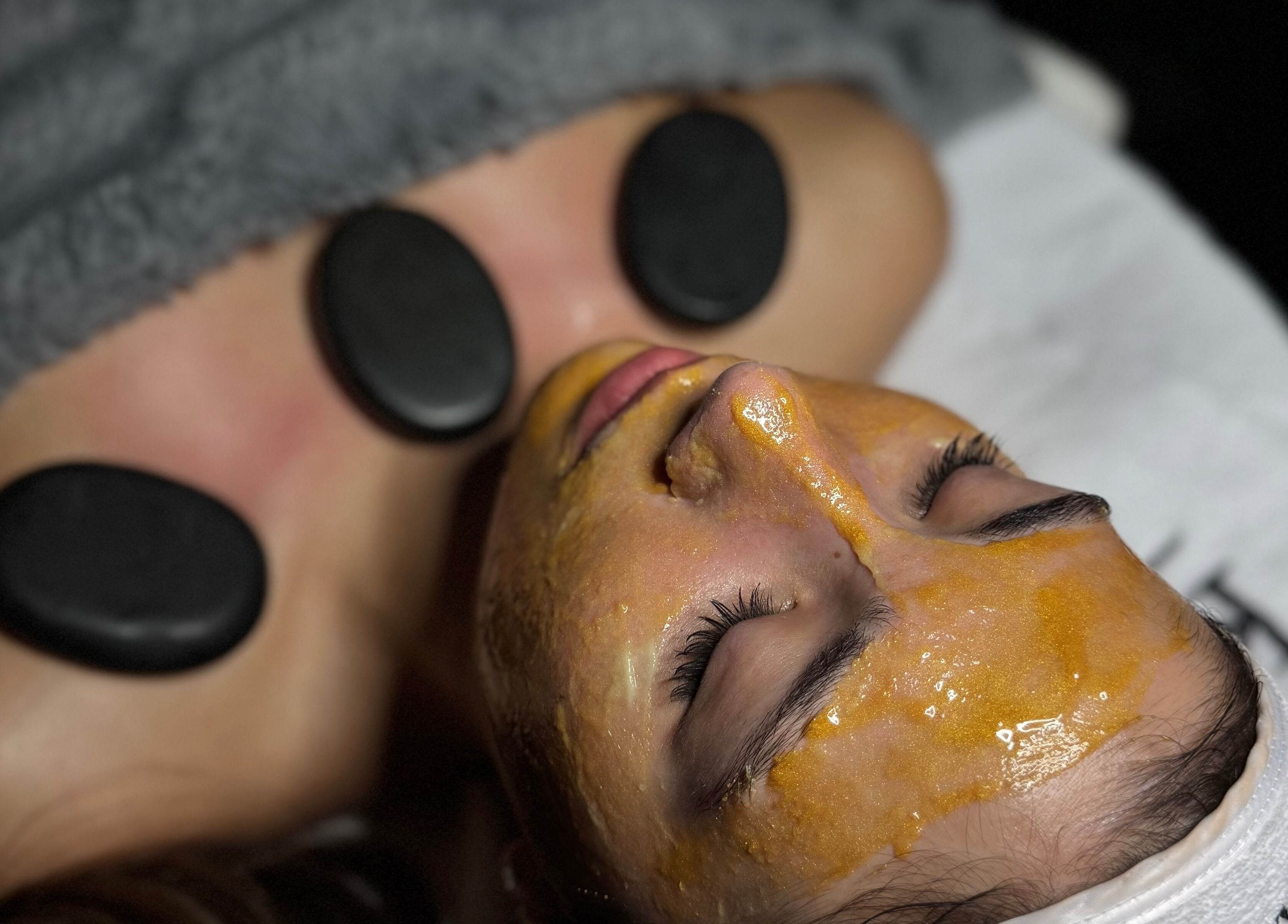 Relaxing facial treatment at Lini's Cosmetics in Vaughan, Ontario, CA with hot stones and golden mask.