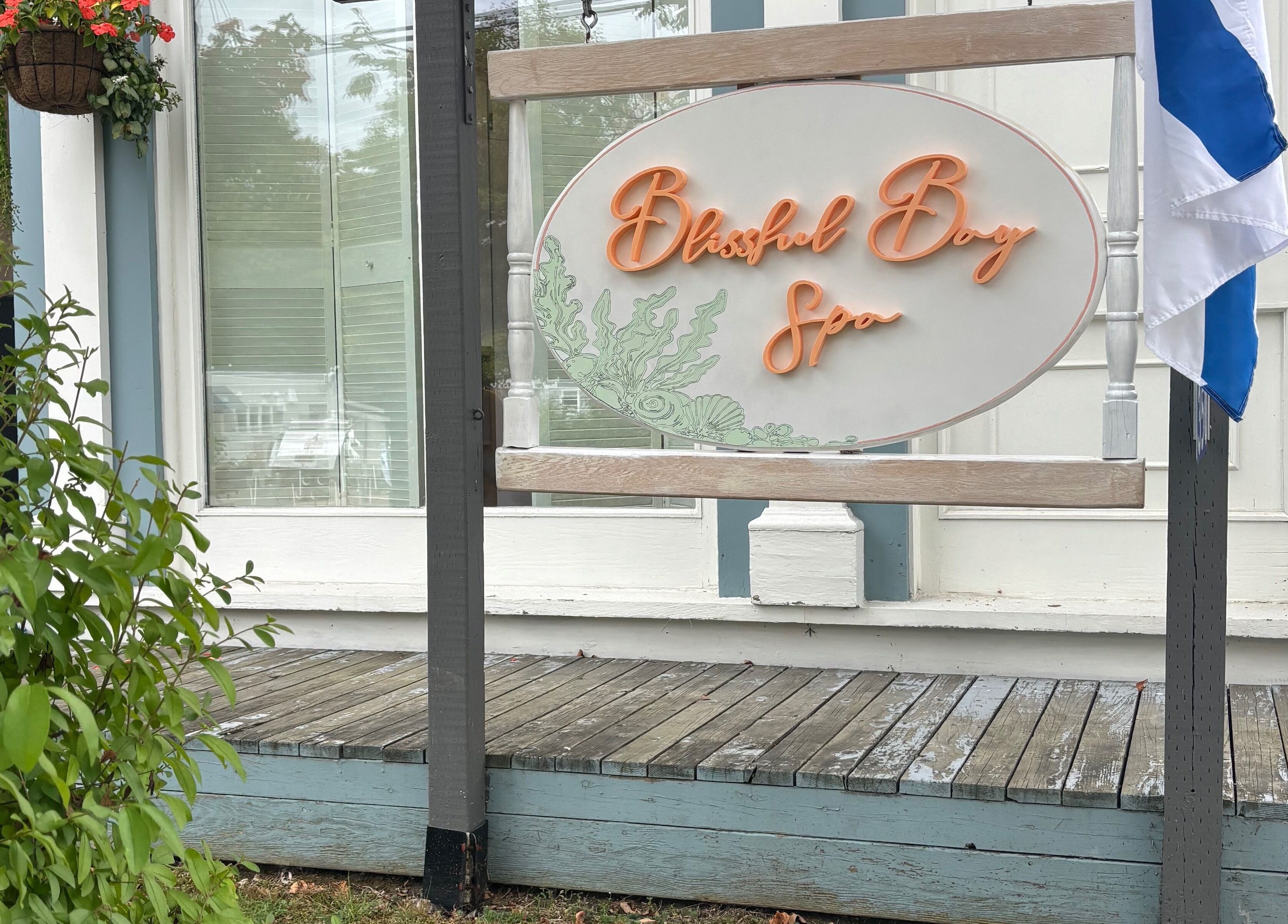 Sign of Blissful Bay Spa with Jennie amidst greenery in Mahone Bay, Nova Scotia, CA, inviting relaxation.