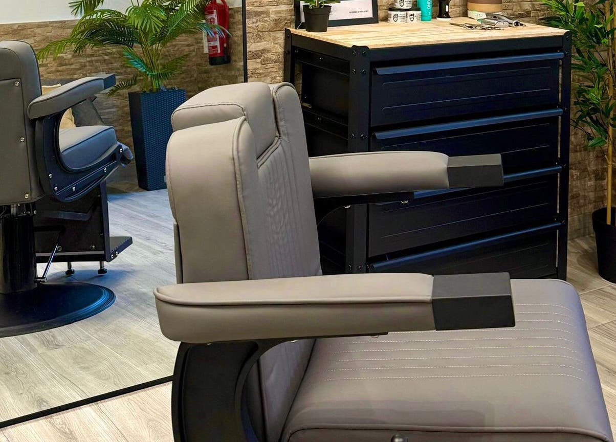 Interior moderno da Barbearia Do Leo em Distrito Da Guarda, Portugal, com poltrona de couro e espelho.