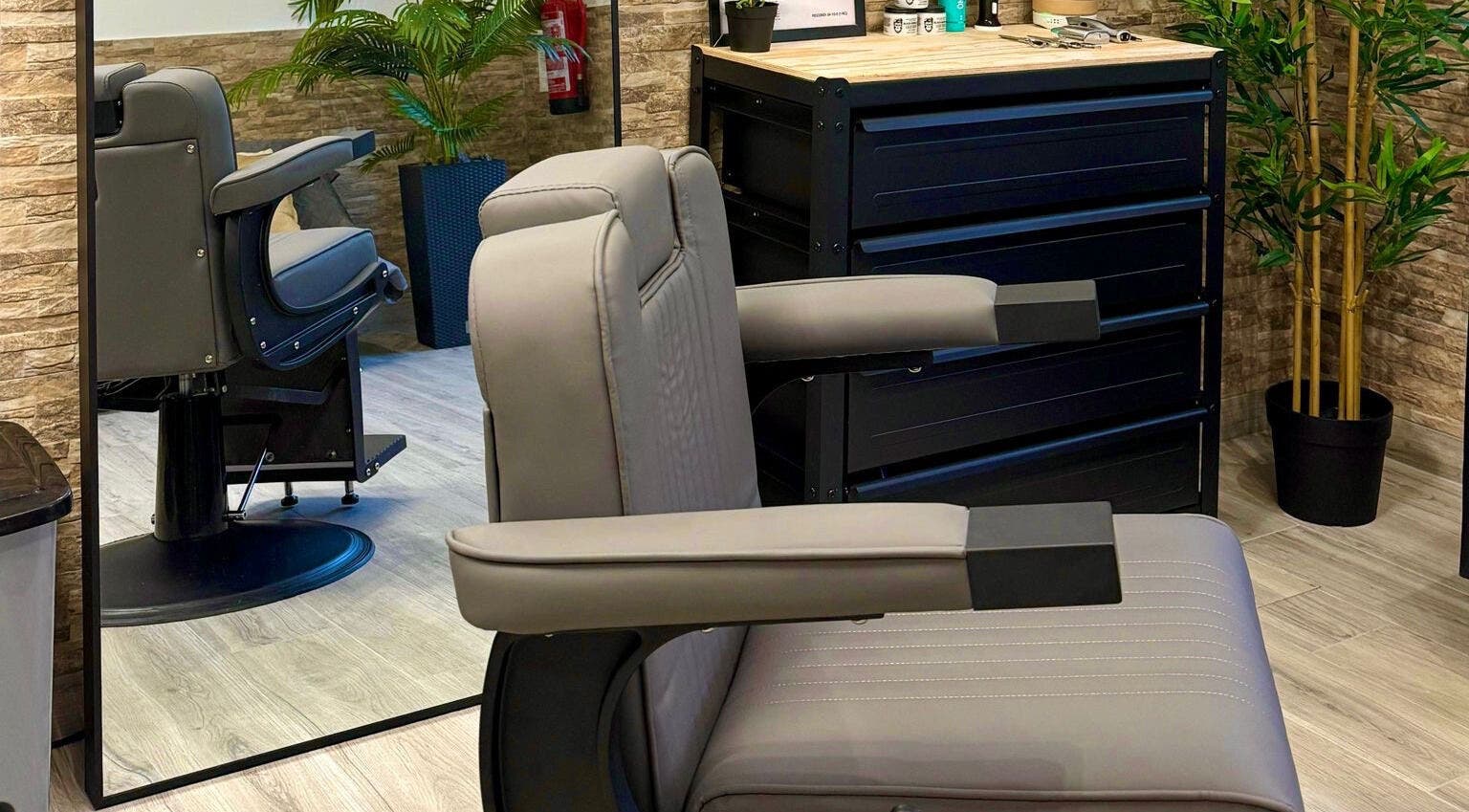 Interior moderno da Barbearia Do Leo em Distrito Da Guarda, Portugal, com poltrona de couro e espelho.