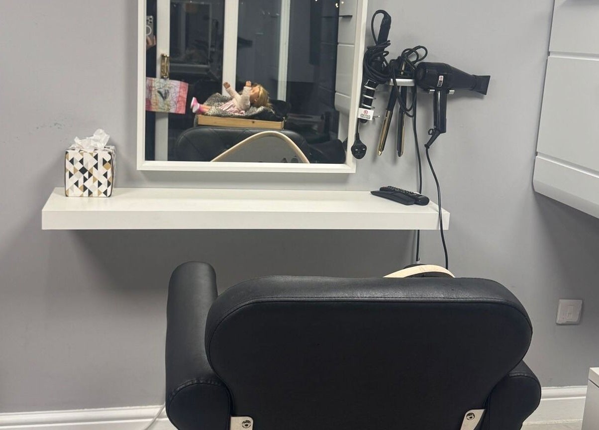 Modern salon setup at Mila Hair Atelier, Epsom, England, GB, featuring a black styling chair and elegant mirror.