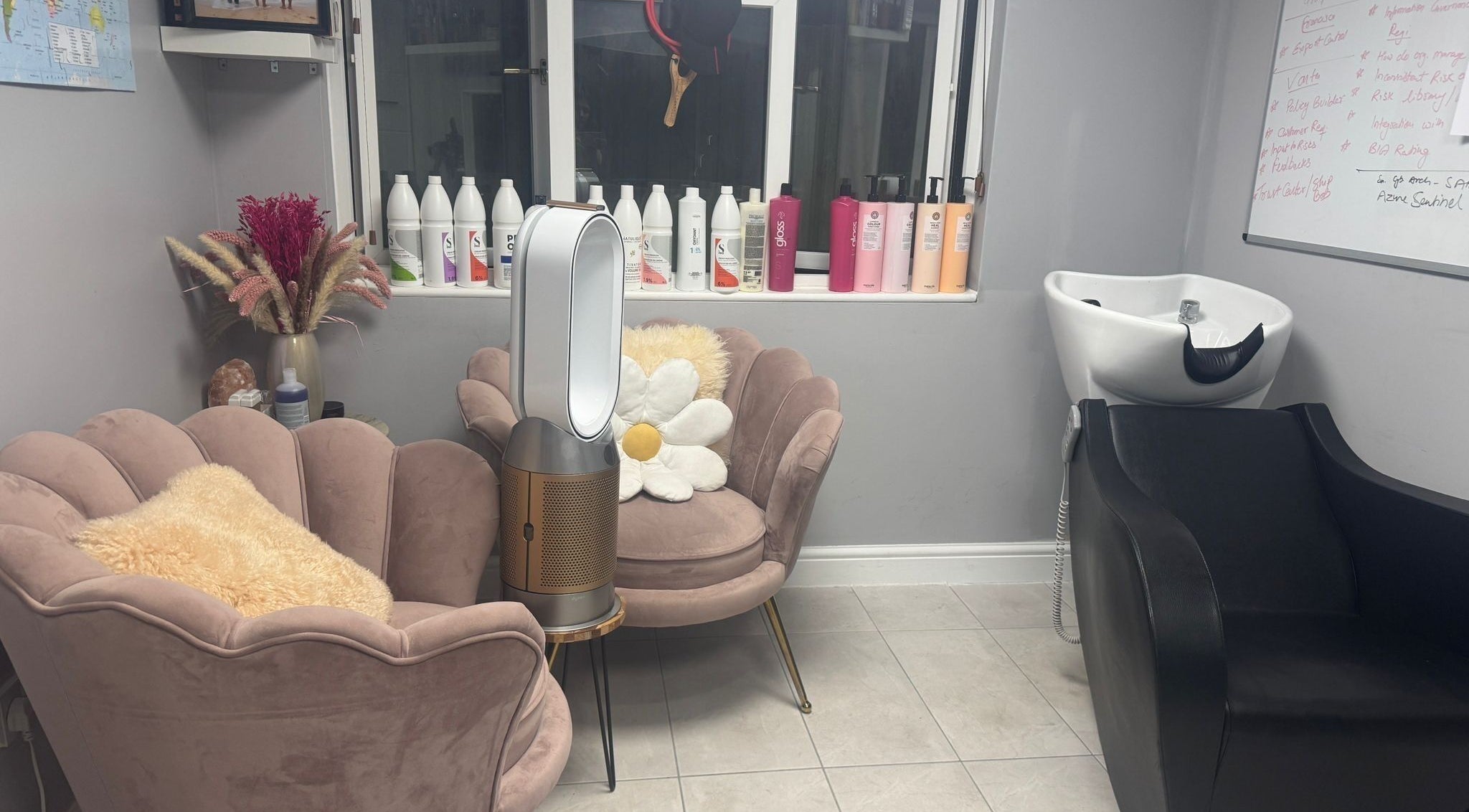 Cozy waiting area at Mila Hair Atelier in Epsom, England, GB, featuring plush chairs and elegant haircare products.