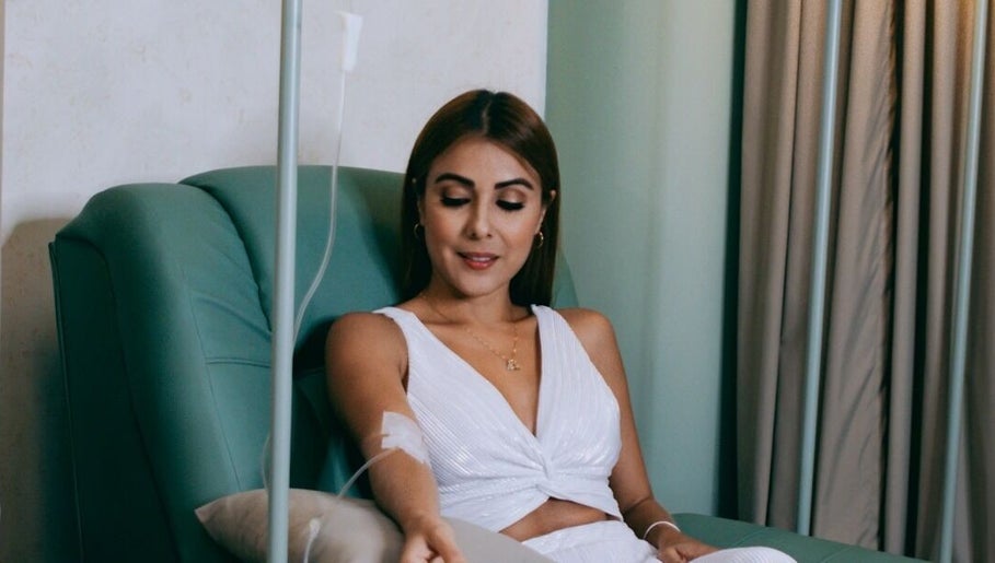 A woman enjoys an IV therapy session at LLERAS MEDICAL LOUNGE, Medellín, Antioquia, CO in a comfortable chair.