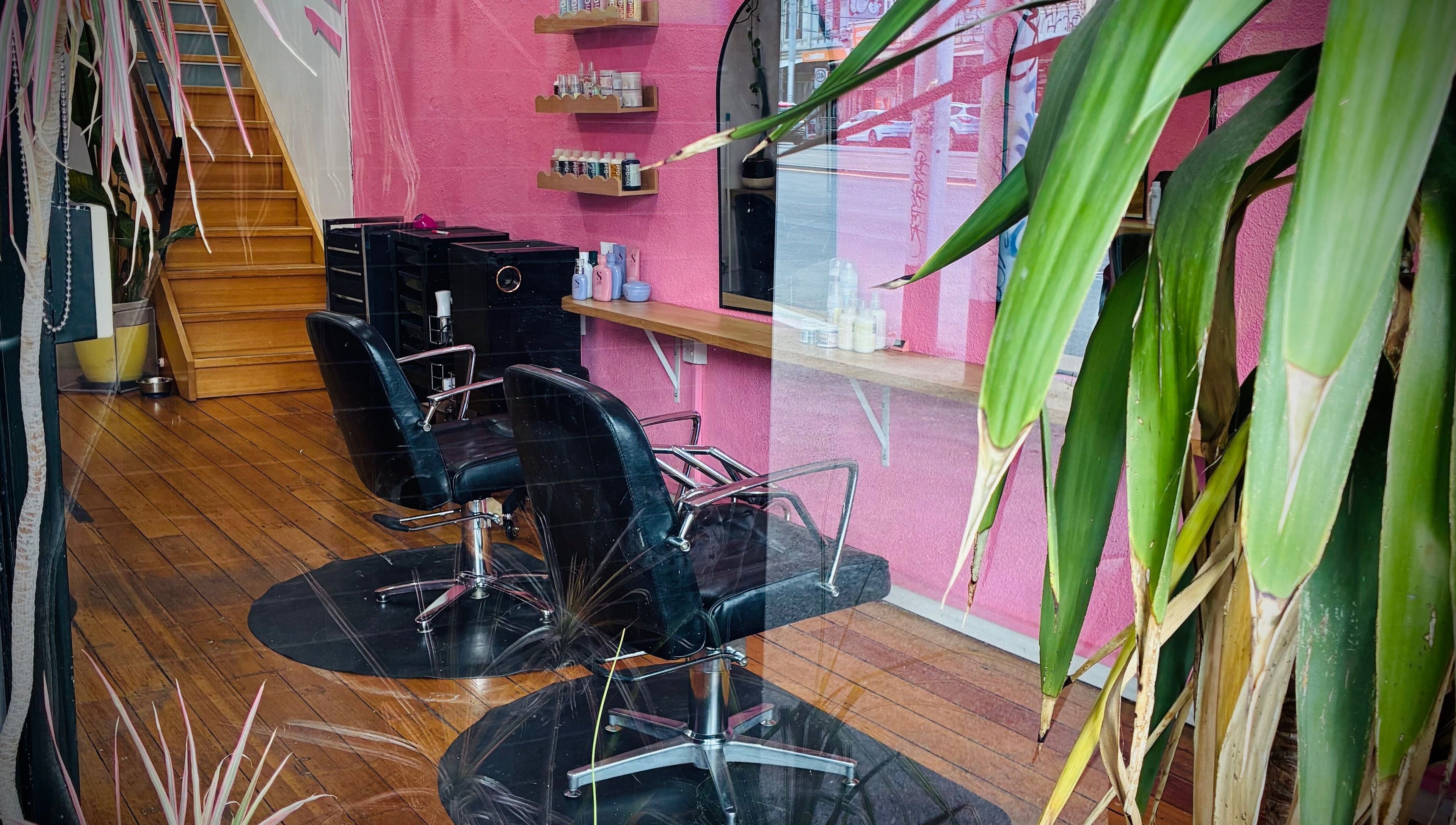 Modern salon interior at Hair By Cat Scally, Melbourne, Victoria, AU, featuring stylish pink walls and salon chairs.