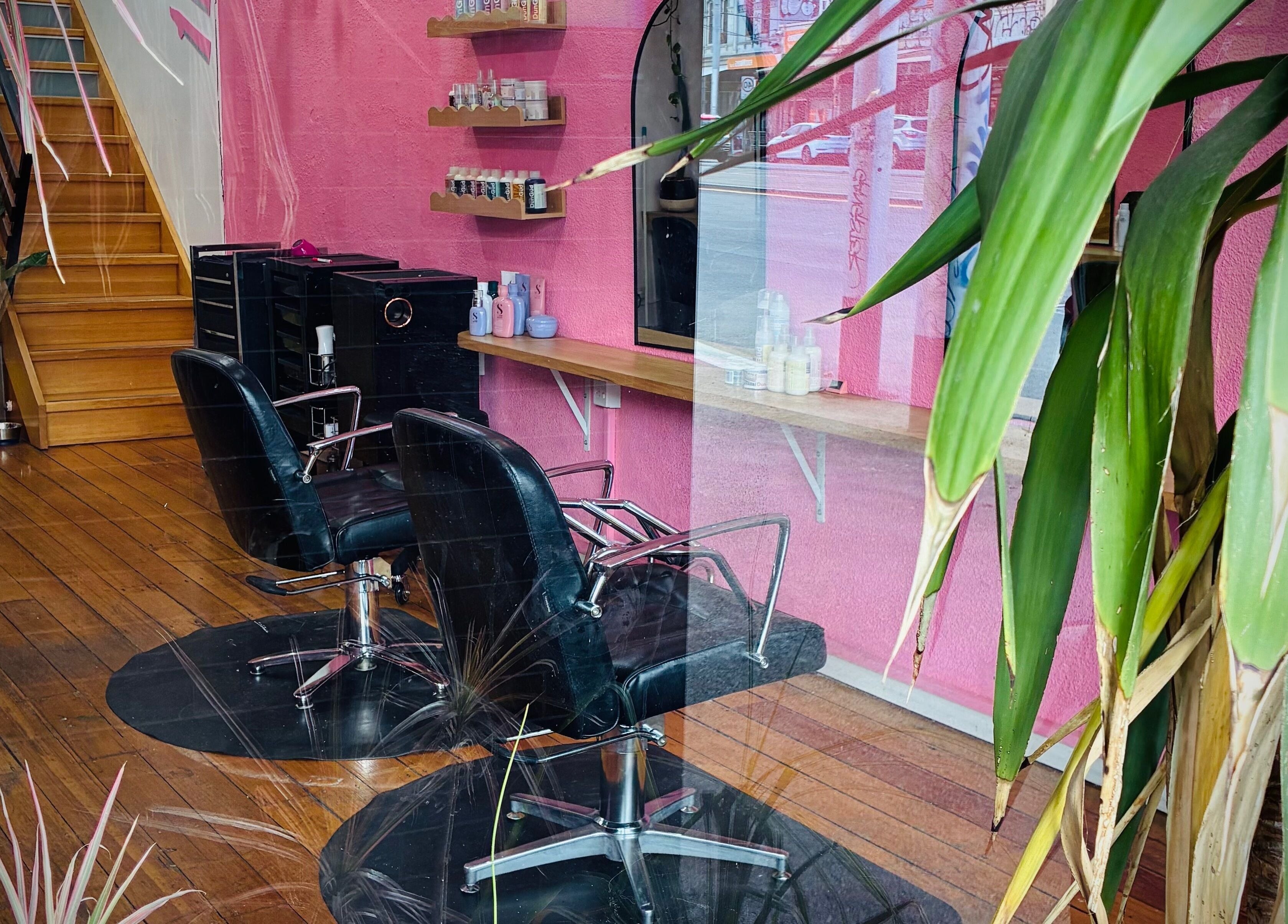 Modern salon interior at Hair By Cat Scally, Melbourne, Victoria, AU, featuring stylish pink walls and salon chairs.