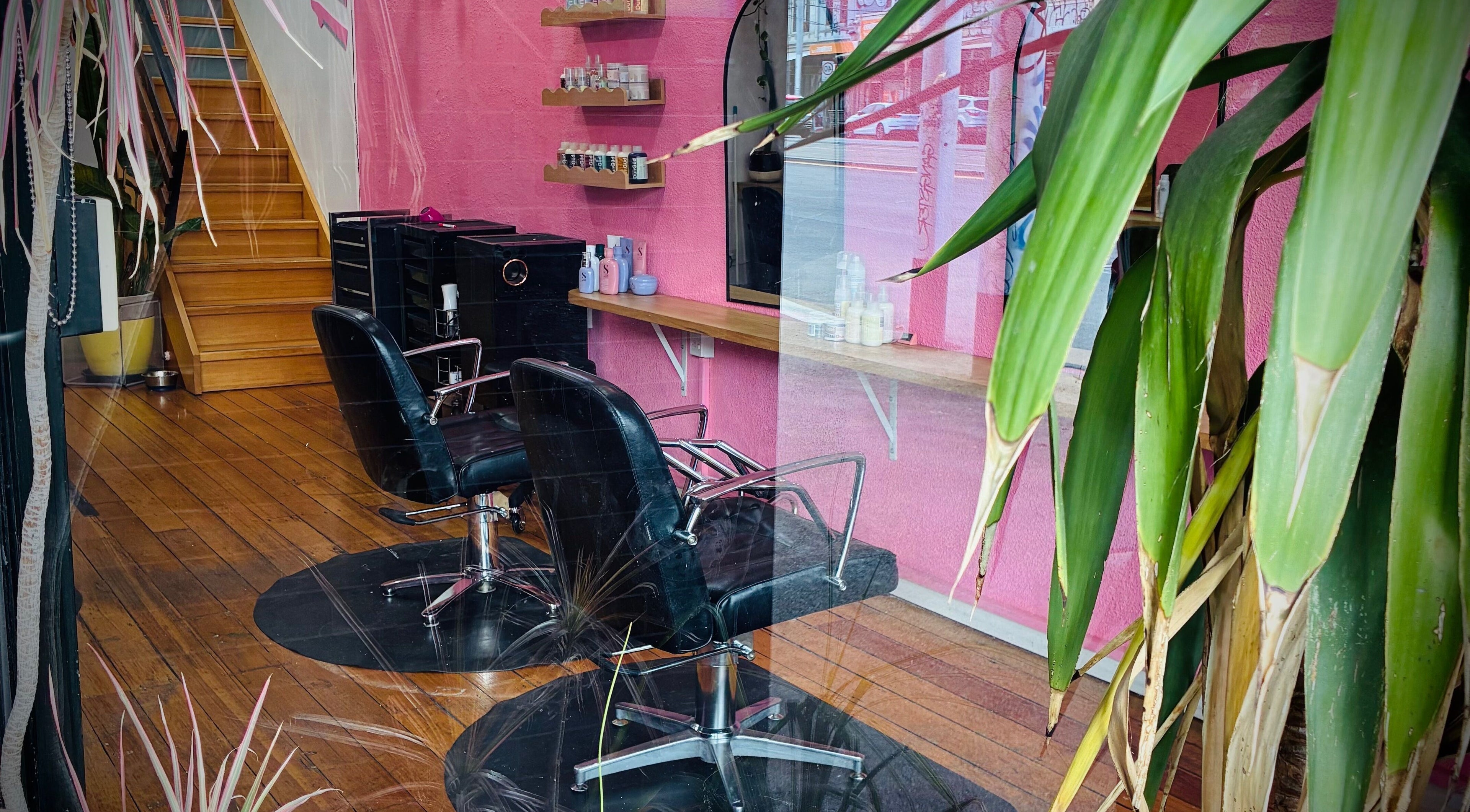 Modern salon interior at Hair By Cat Scally, Melbourne, Victoria, AU, featuring stylish pink walls and salon chairs.