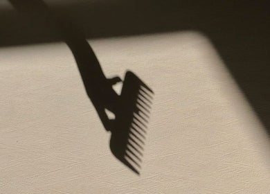 Shadow of a comb on textured surface at MaddyLox, Toronto, Ontario, CA, exemplifying elegance and style.