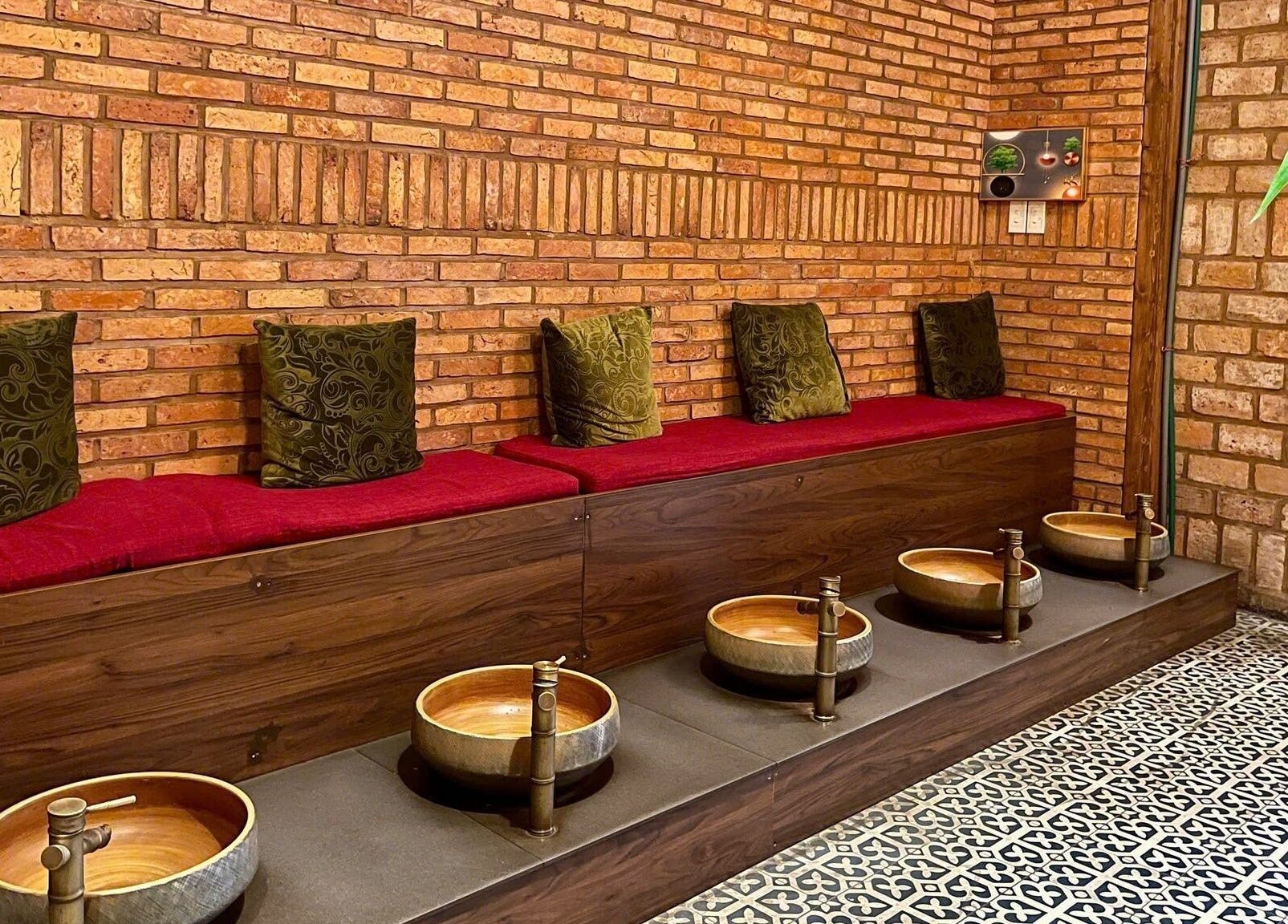 Góc thư giãn ấm cúng tại Panda Spa, Đà Nẵng, Đà Nẵng, VN với tường gạch và chậu ngâm chân.