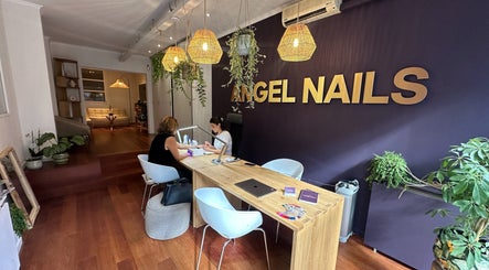 Interior of Angel Nails in Uccle, Bruxelles with a client receiving a manicure at a stylish wooden desk.