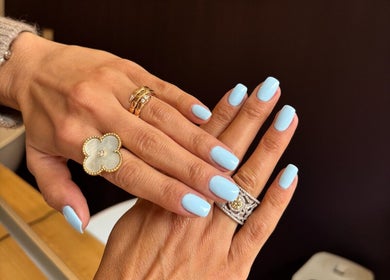 Elegant light blue manicure at Angel Nails, Uccle, Bruxelles, BE showcases stylish nail art and fine rings.