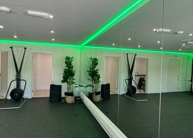 Modern fitness studio at Amy Pickett Fitness, Sawbridgeworth, England, GB with mirrors and green lighting.