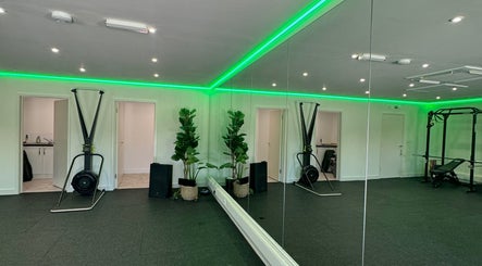Modern fitness studio at Amy Pickett Fitness, Sawbridgeworth, England, GB with mirrors and green lighting.