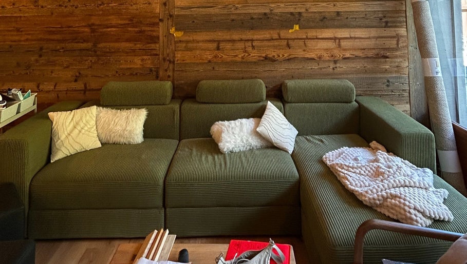 Salon confortable au Alpine Active Lodge, Nendaz, Valais, CH, avec canapé vert et coussins moelleux.