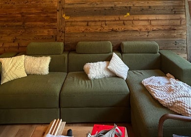 Salon confortable au Alpine Active Lodge, Nendaz, Valais, CH, avec canapé vert et coussins moelleux.