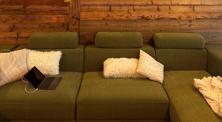 Canapé vert avec coussins moelleux à Alpine Active Lodge, Nendaz, Valais, CH.