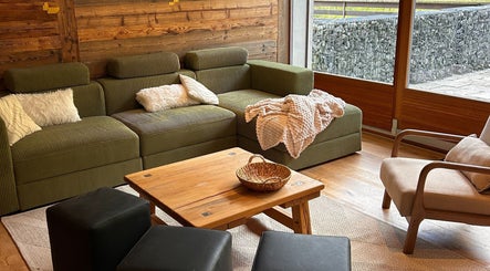 Espace salon confortable à Alpine Active Lodge, Nendaz, Valais, CH avec canapé vert et table en bois.