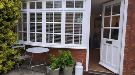 Charming entrance to Stripped Beauty in Basingstoke, England with open door and garden plants.