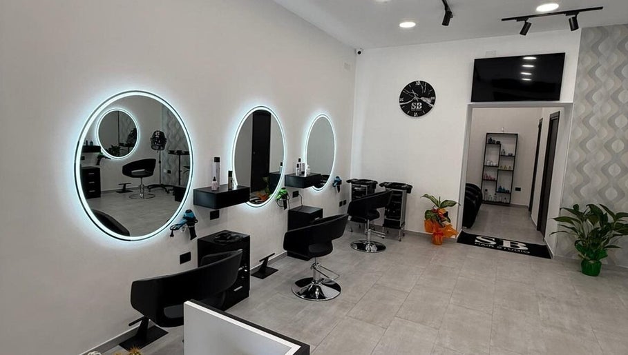 Interno moderno di Sb_HairStudio a Cimitile, Campania, IT con specchi rotondi e sedie nere.