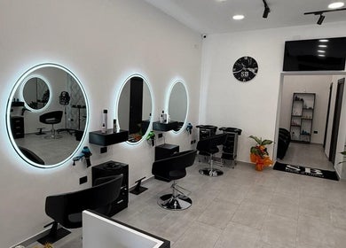 Interno moderno di Sb_HairStudio a Cimitile, Campania, IT con specchi rotondi e sedie nere.