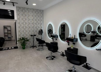 Interno elegante di Sb_HairStudio a Cimitile, Campania, IT con specchi rotondi illuminati e postazioni moderne.