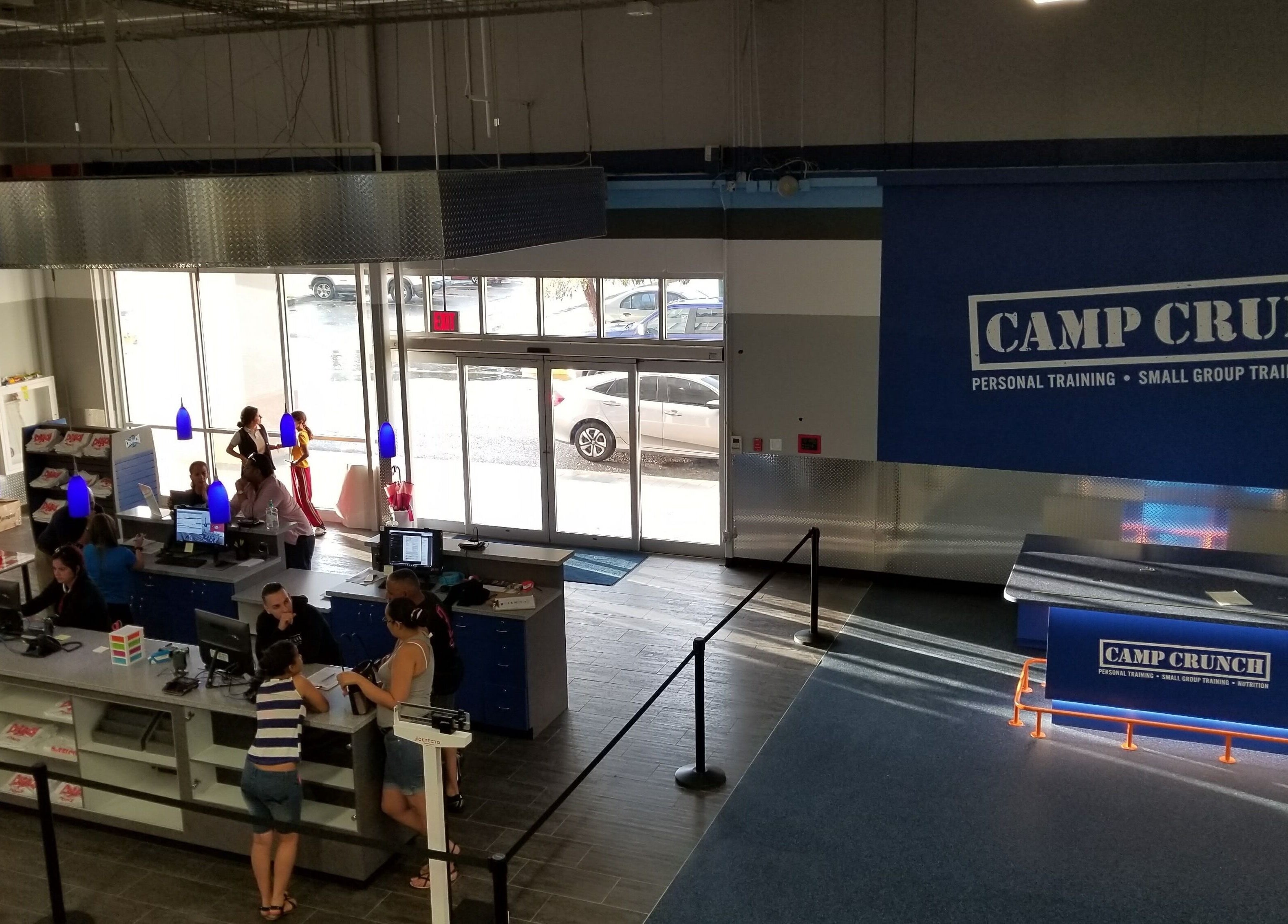 Área de recepción en Crunch Fitness Ponce, Ponce, PR con clientes y personal en actividad.