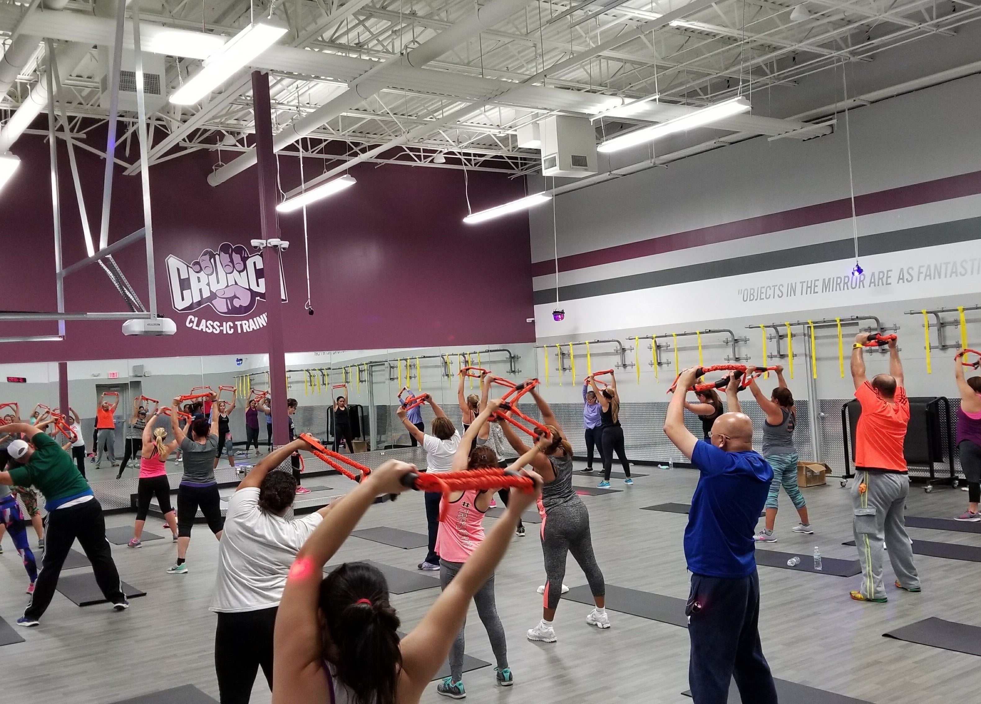 Clase de ejercicio grupal en Crunch Fitness Ponce, Ponce, PR, con instructora y participantes activos.