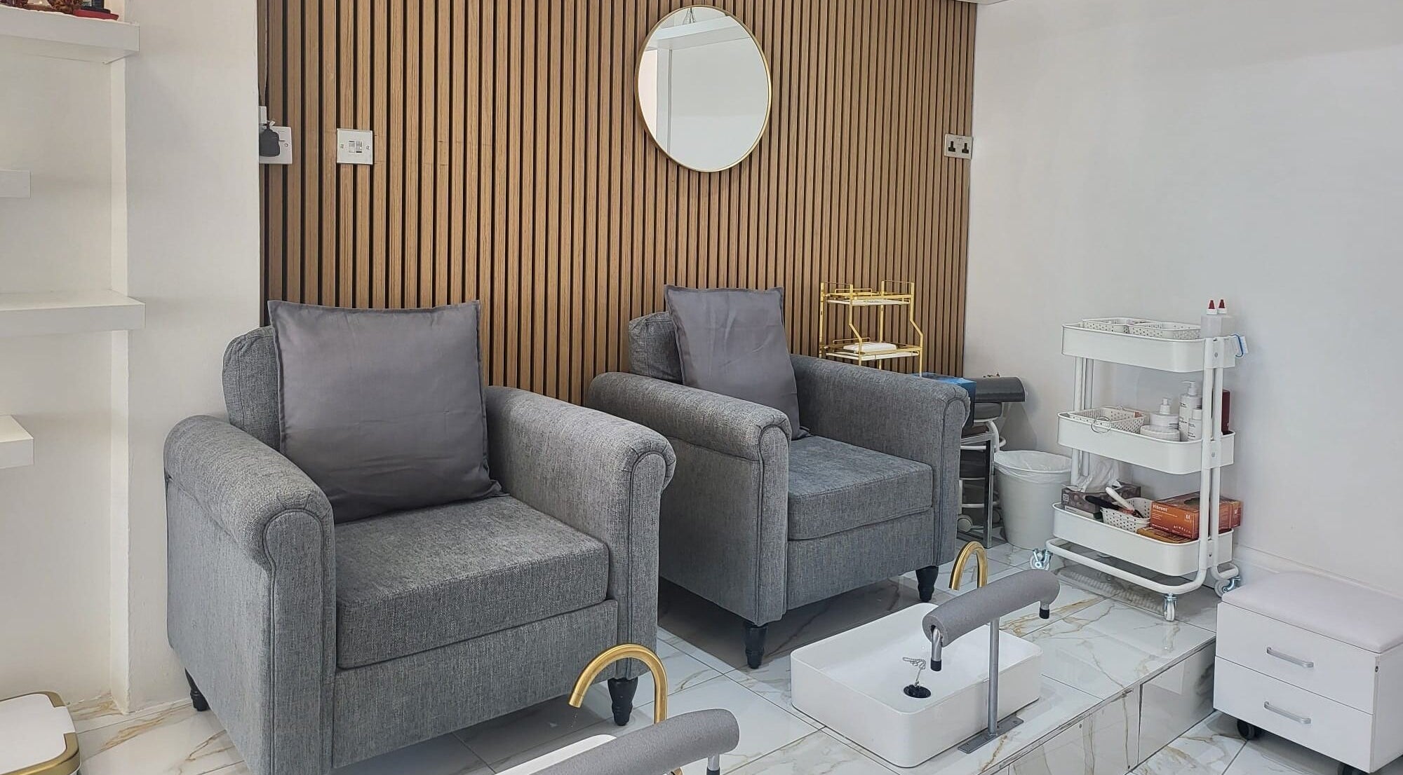Cozy grey chairs with foot spa setup at Ny Beauty Hub London, located in London, England, GB.