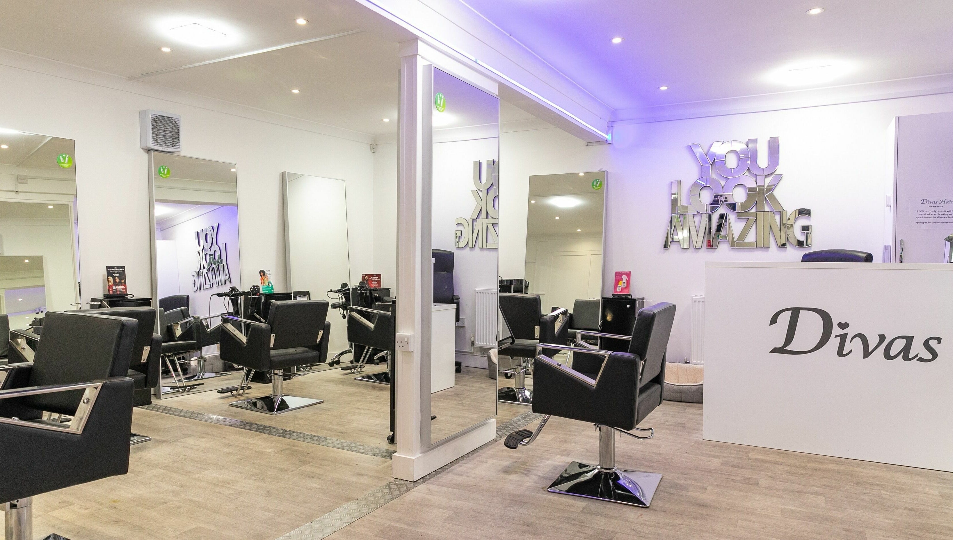 Chic salon interior at Divas Hair, located in Cheshunt, England, GB, with stylish chairs and modern decor.