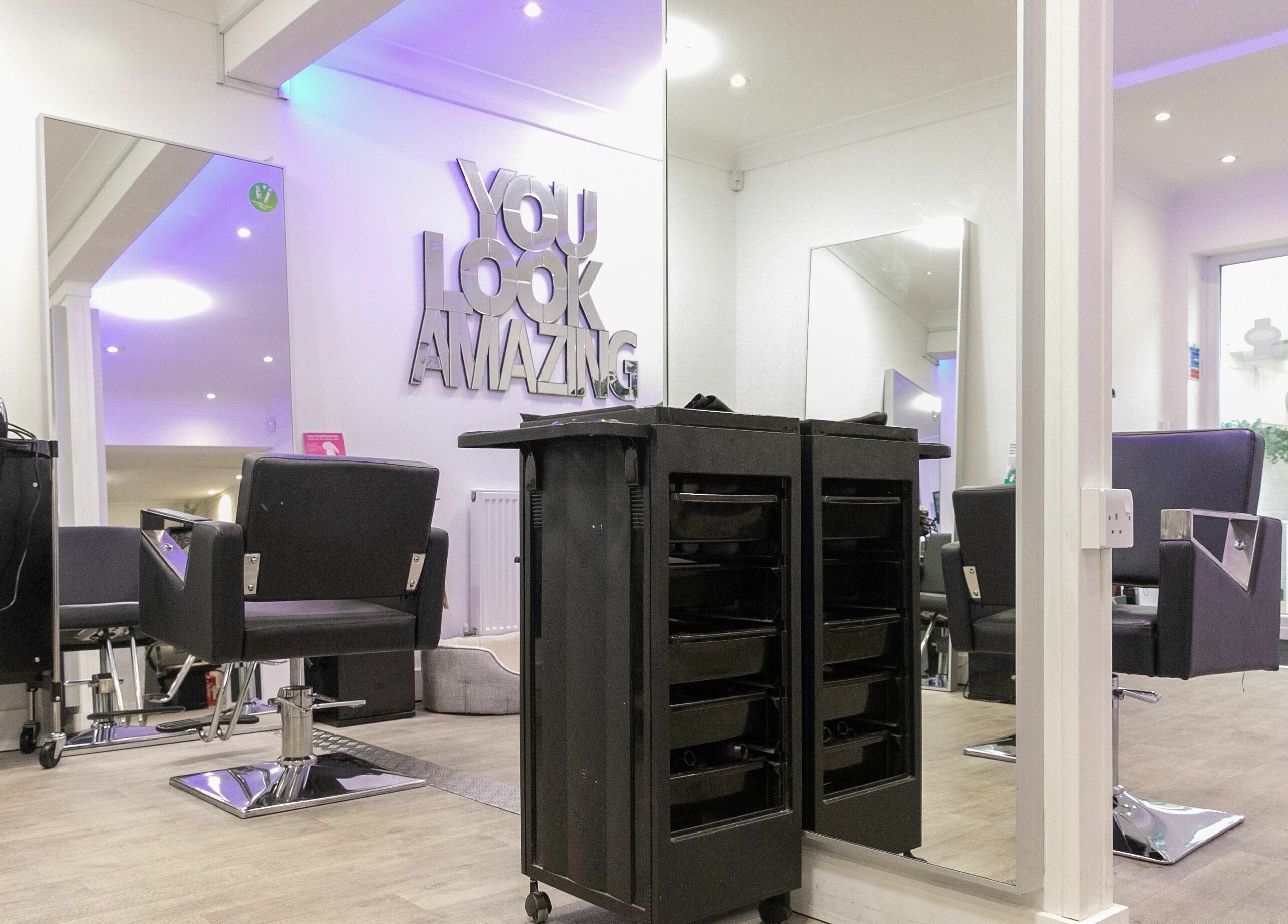 Modern salon interior at Divas Hair, Cheshunt, England, GB with stylish chairs and vanity mirrors.