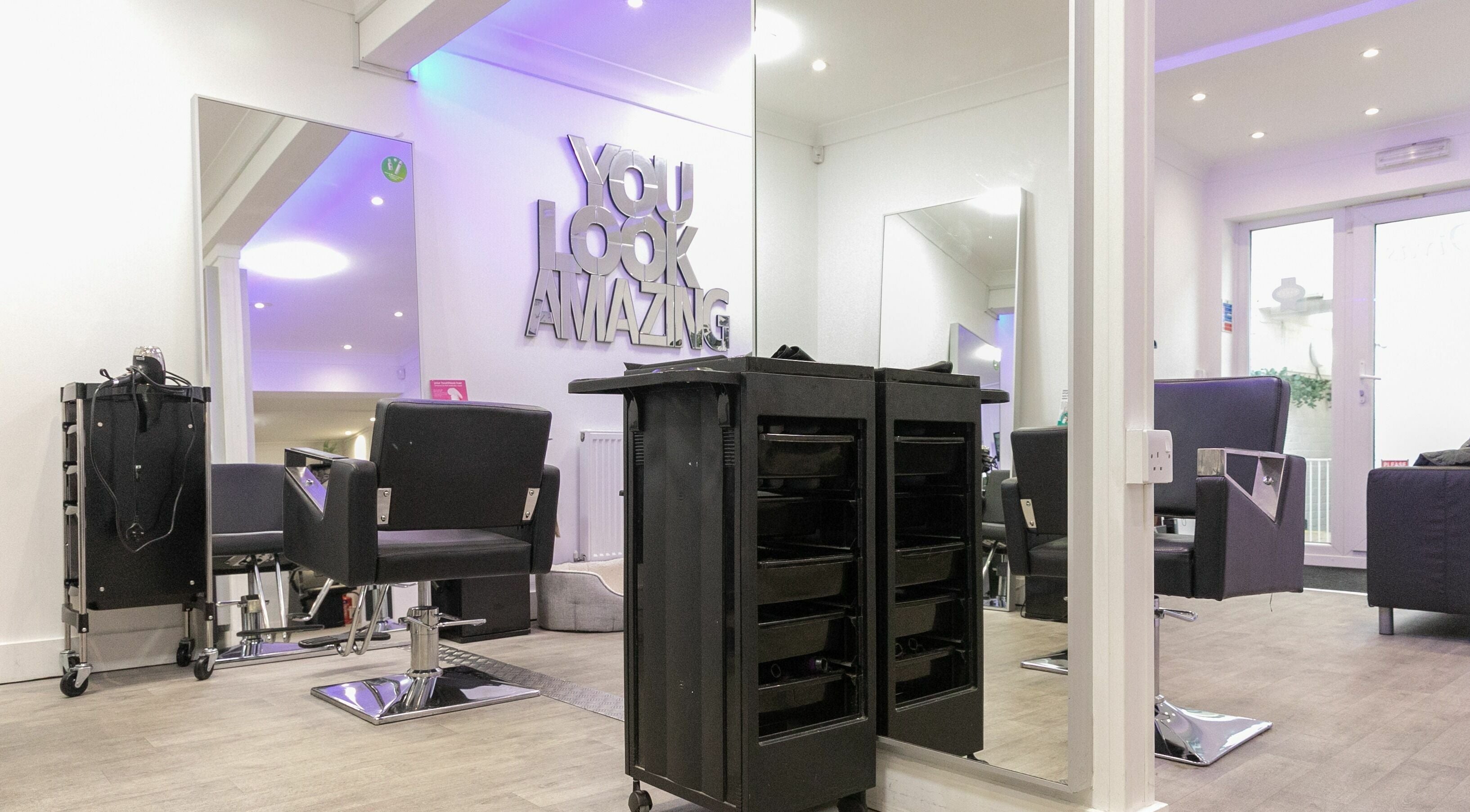 Modern salon interior at Divas Hair, Cheshunt, England, GB with stylish chairs and vanity mirrors.