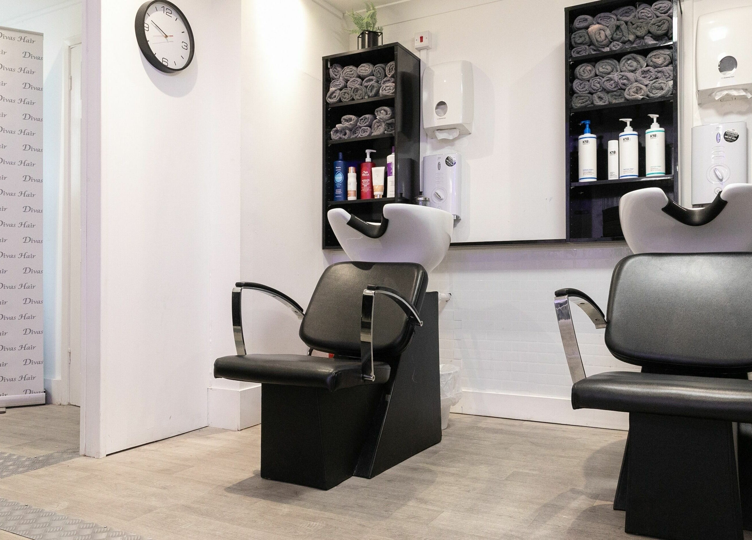 Modern shampoo stations at Divas Hair, Cheshunt, England, GB with sleek chairs and towels.