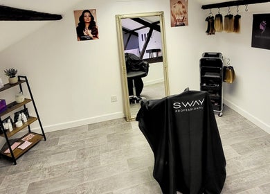 Inside BeyondLengthEssex salon, Dunmow, England, GB. Elegant mirror and professional styling chairs featured.