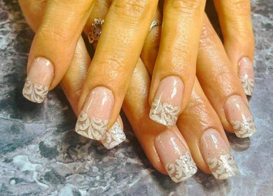 Elegant nail art design at Mystique Nails in Alpena, Michigan, US showcasing intricate white patterns.