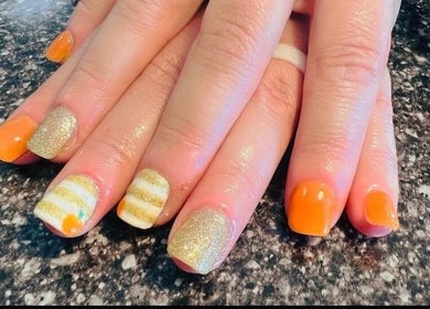 Stylish orange and gold manicured nails at Mystique Nails in Alpena, Michigan, US.