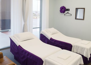 Mesa, Arizona, US 的 Releaf Massage & Health Spa 含紫色装饰的双床治疗室。
