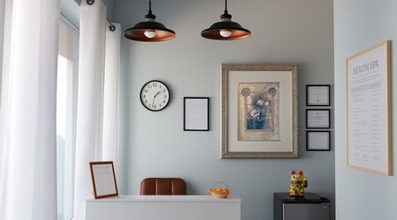 Reception area at Releaf Massage & Health Spa in Mesa, Arizona, US, featuring framed art, clock, and maneki-neko.