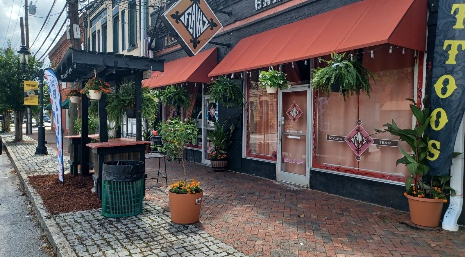 Charming facade of Kay’s Kraft in Lithonia, Georgia, US, with vibrant plants and rustic brickwork.