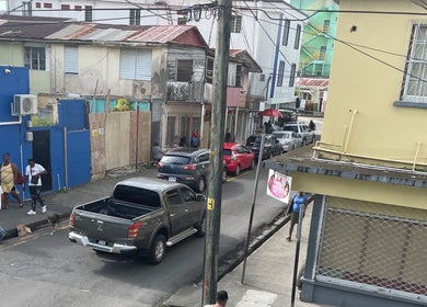 Street view near Nika’s Styles & Smiles in Castries, LC, showcasing colorful buildings and local activity.