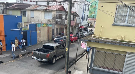 Street view near Nika’s Styles & Smiles in Castries, LC, showcasing colorful buildings and local activity.