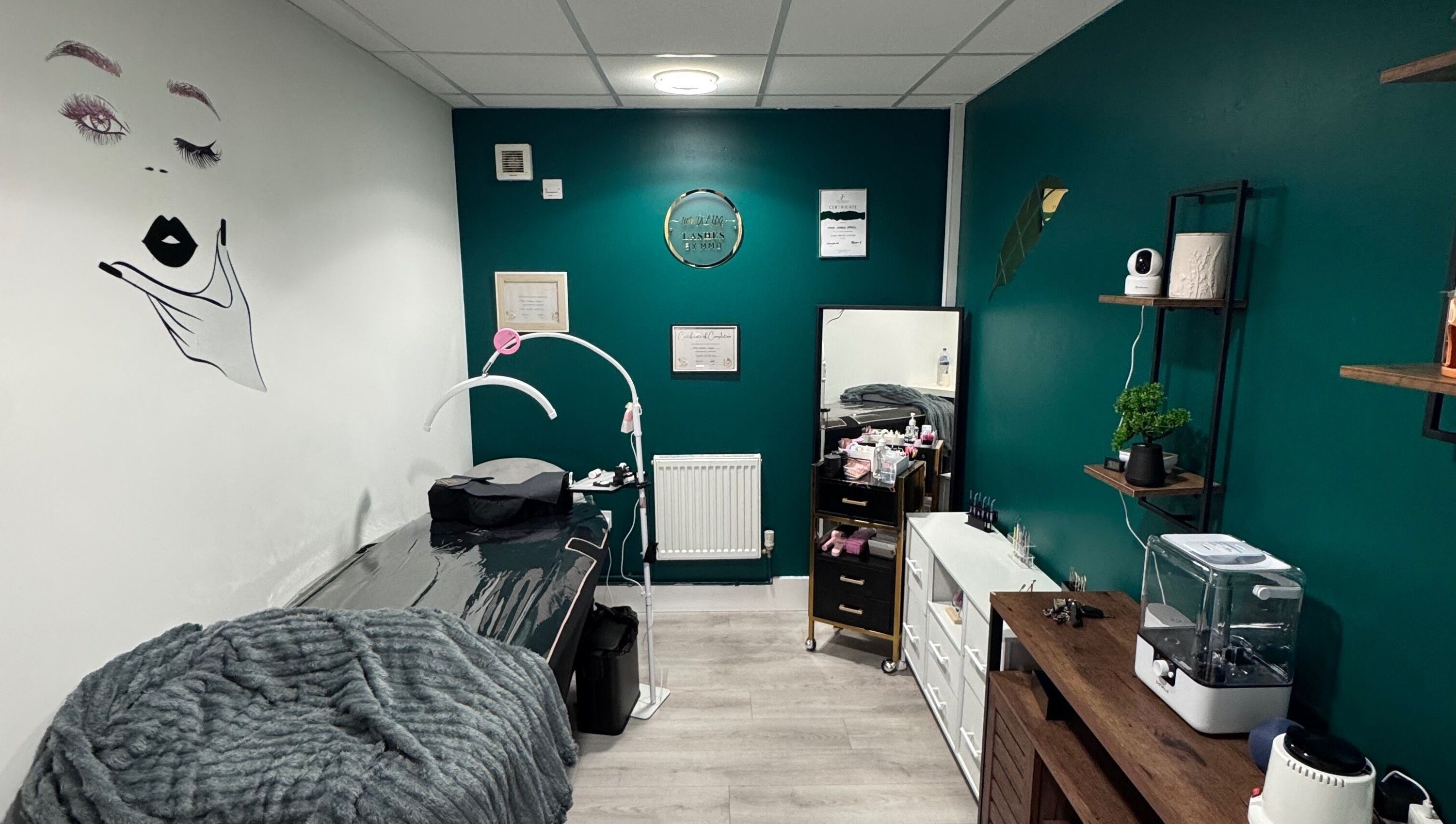 Cozy MMDÉLUXE LASHES salon in Swindon, England, GB with teal walls and treatment table.