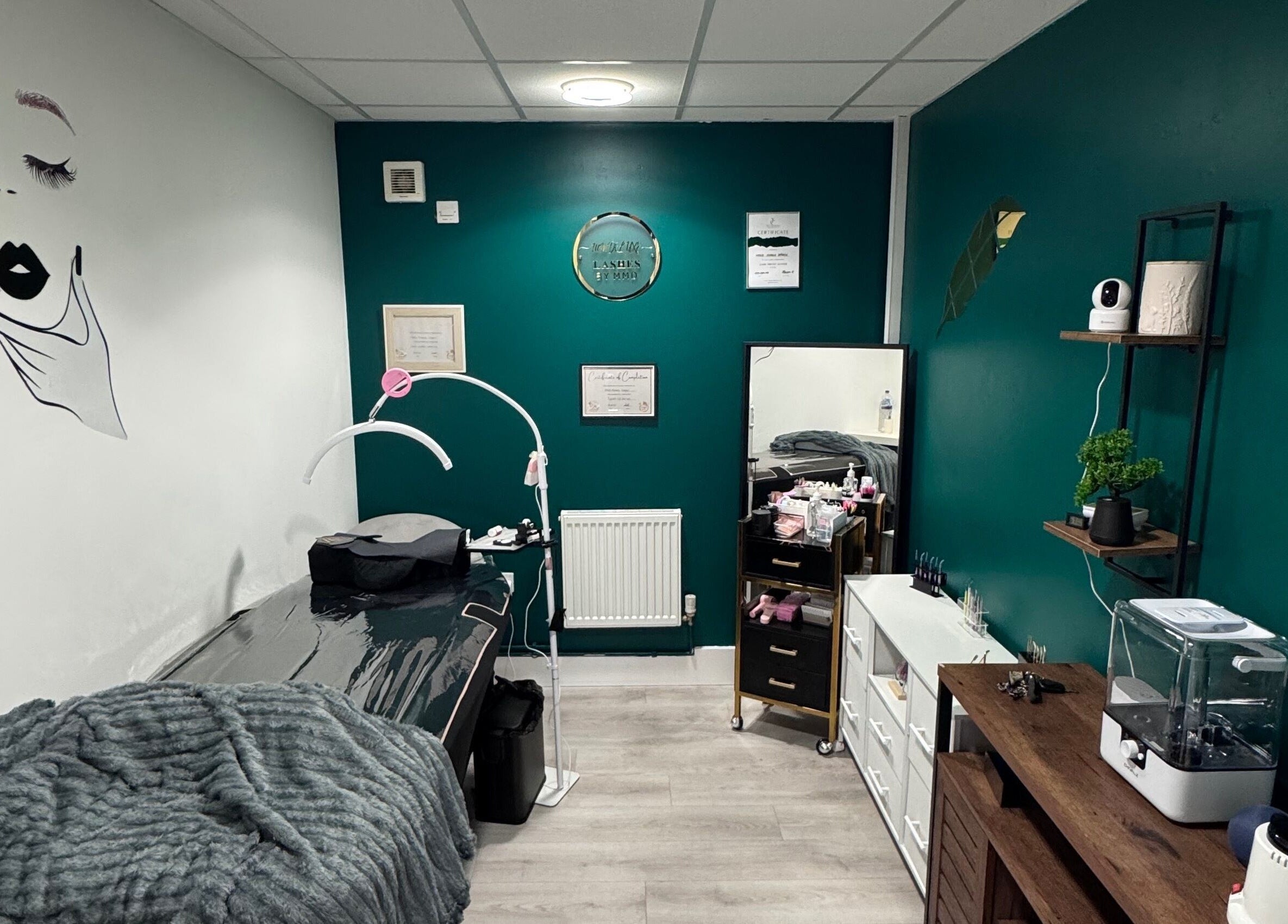 Cozy MMDÉLUXE LASHES salon in Swindon, England, GB with teal walls and treatment table.