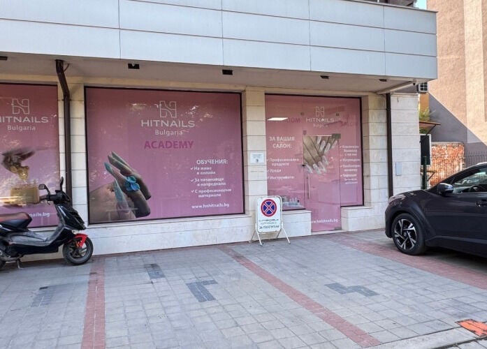 Фасада на Hit Nails Bulgaria, София, Област София, BG с витрини и паркирани автомобили.