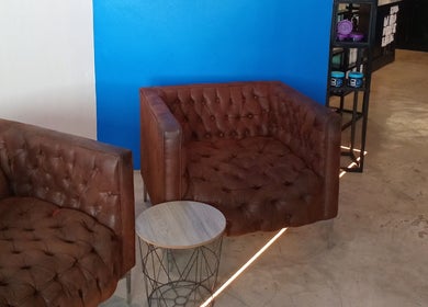 Cozy leather chairs and a small table at St Tropez Homme Barbershop in Cape Town, Western Cape, ZA.