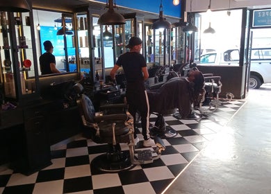 Stylish interior of St Tropez Homme Barbershop in Cape Town, Western Cape, ZA, featuring modern black chairs.