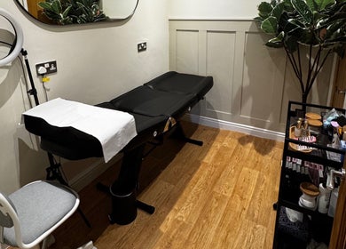 AJ Lash & Brow's serene treatment room in Bristol, England, GB featuring a sleek black beauty bed.